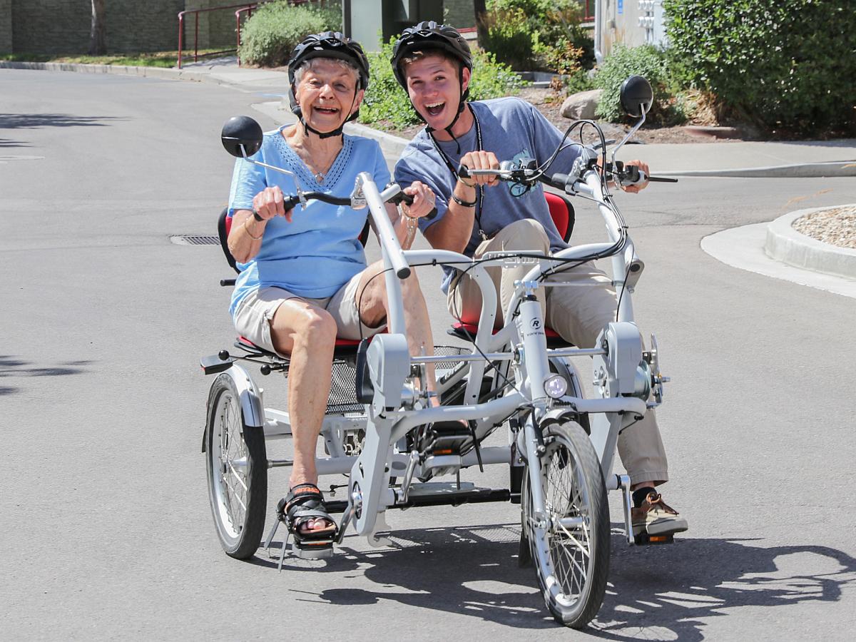Older woman and man riding on an adaptive bicycle