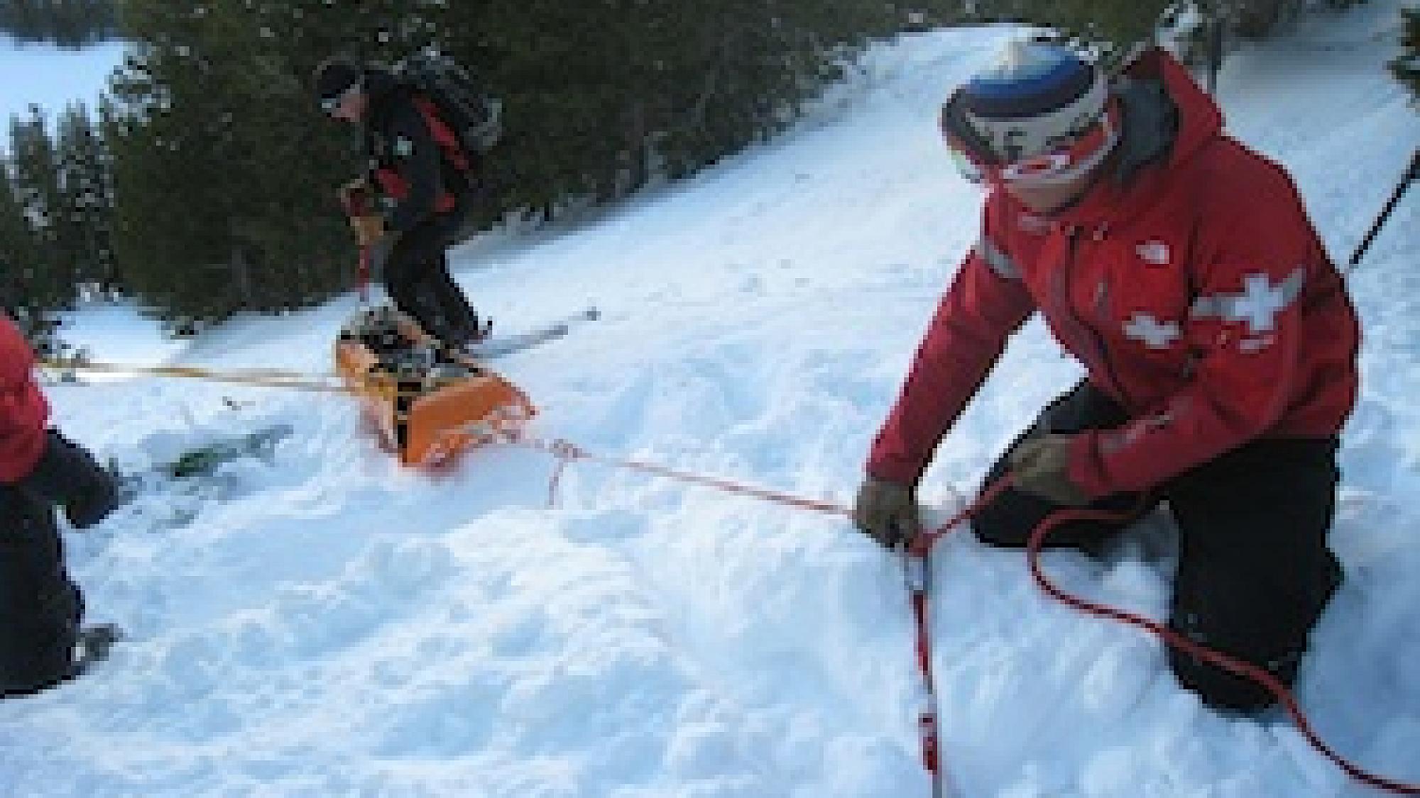 Search and rescue crew pulling an injured person through the snow