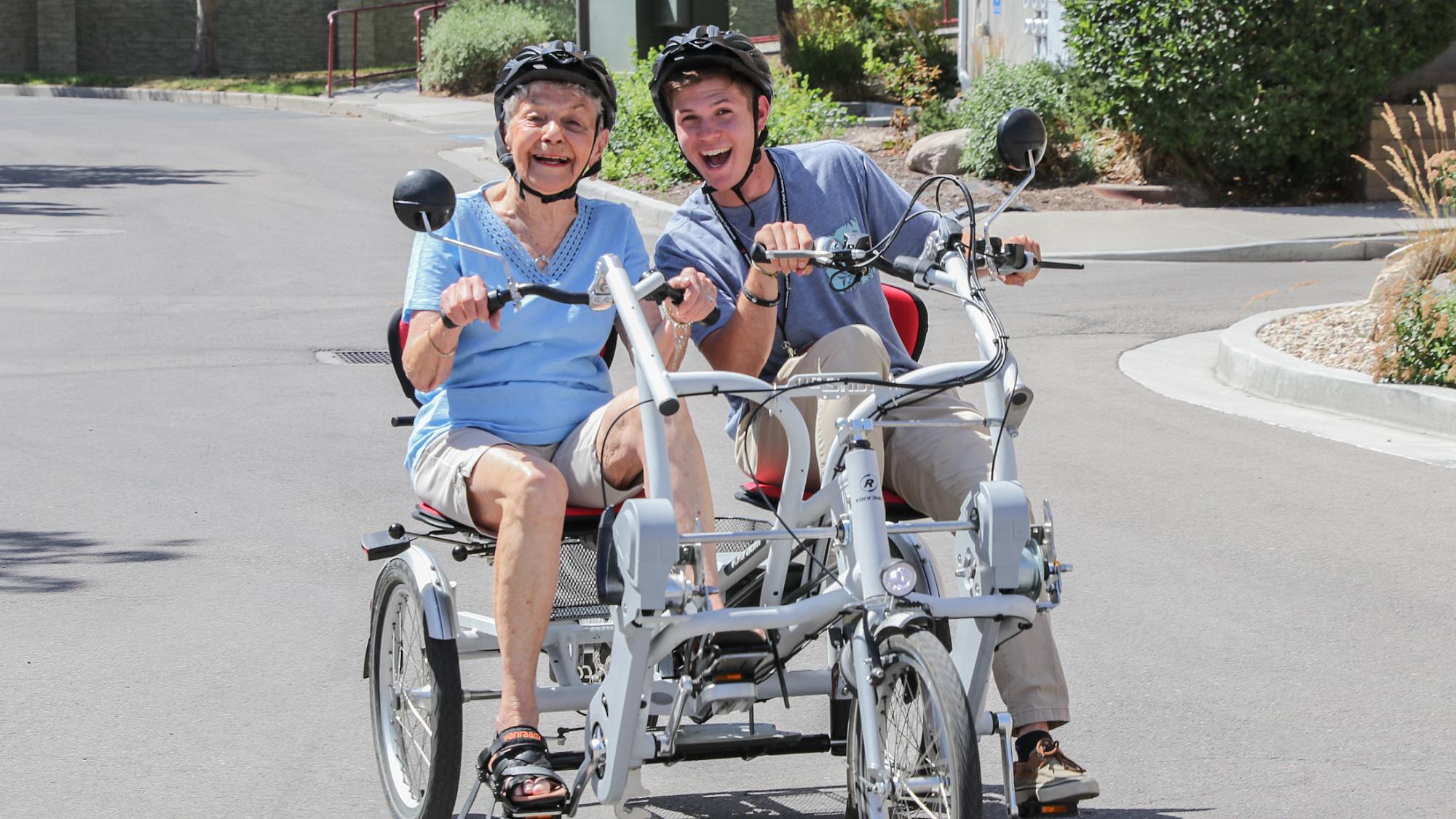 Older woman and man riding on a tandem bicycle